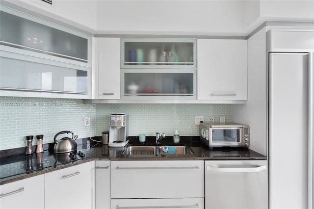 kitchen featuring dark stone counters, white cabinetry, dishwasher, and a sink