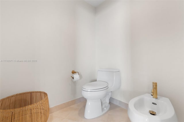 half bathroom featuring toilet, baseboards, a bidet, and tile patterned floors