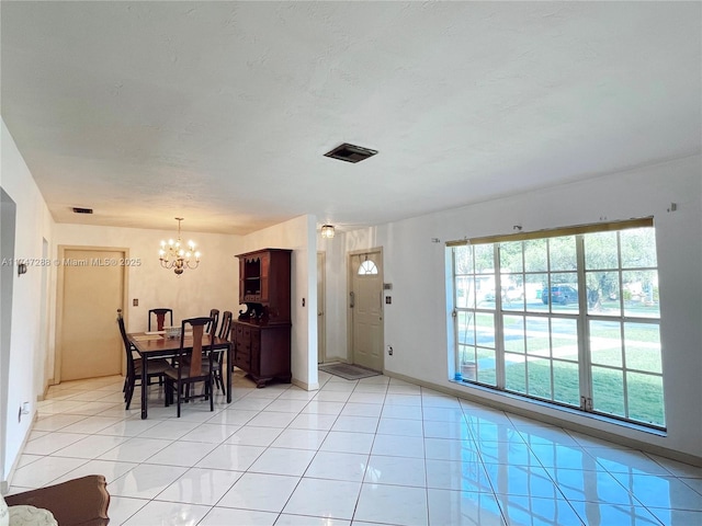 dining space with light tile patterned flooring, a notable chandelier, and a textured ceiling