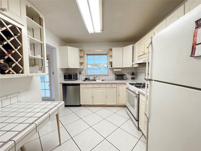 kitchen with stainless steel appliances, tile countertops, and backsplash