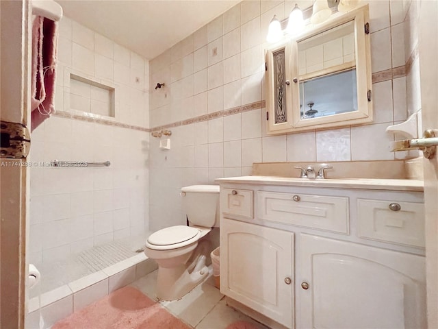 bathroom with tasteful backsplash, toilet, a tile shower, tile walls, and vanity