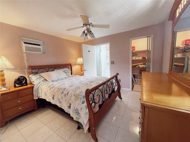 bedroom featuring a closet, a spacious closet, an AC wall unit, ceiling fan, and light tile patterned floors