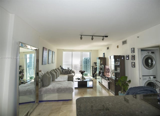 living area with stacked washing maching and dryer, rail lighting, visible vents, and floor to ceiling windows