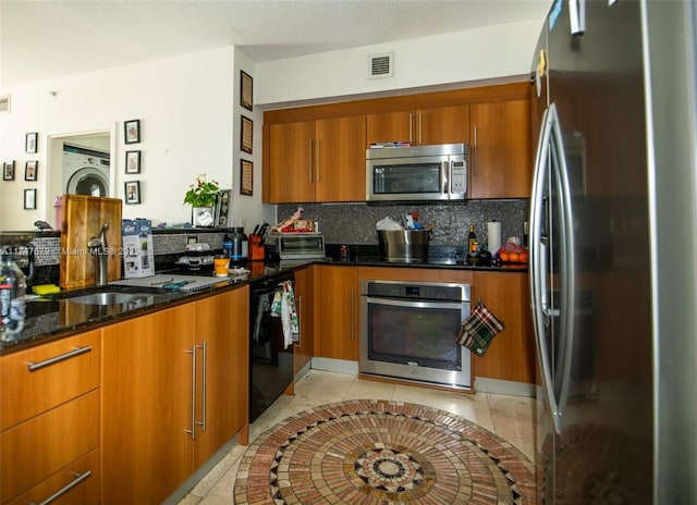 kitchen featuring tasteful backsplash, visible vents, dark stone counters, appliances with stainless steel finishes, and brown cabinets