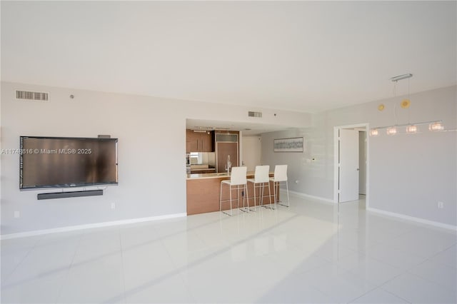 living area with light tile patterned floors, baseboards, and visible vents