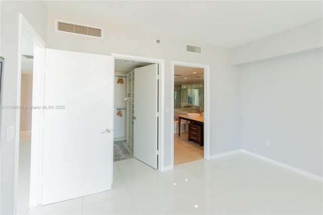 unfurnished bedroom featuring a spacious closet, baseboards, a closet, and visible vents