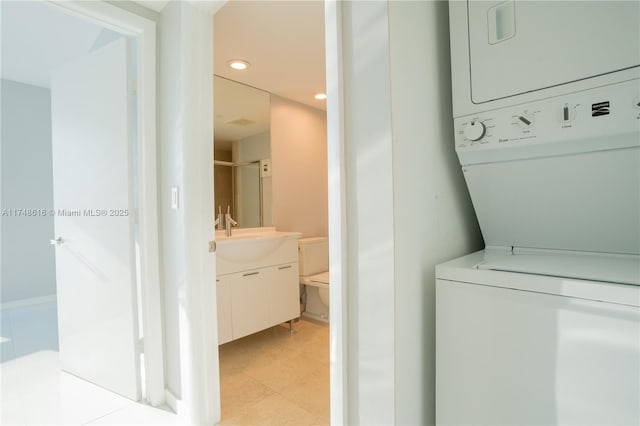 clothes washing area featuring laundry area, light floors, stacked washing maching and dryer, recessed lighting, and a sink