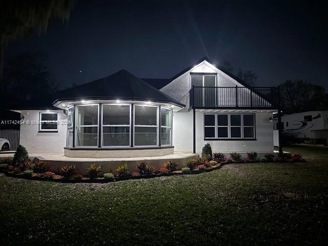 view of front of house with a yard and a balcony