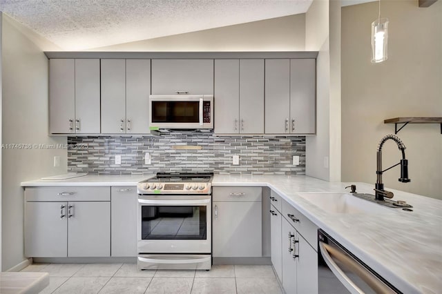 kitchen featuring appliances with stainless steel finishes, gray cabinets, sink, and vaulted ceiling