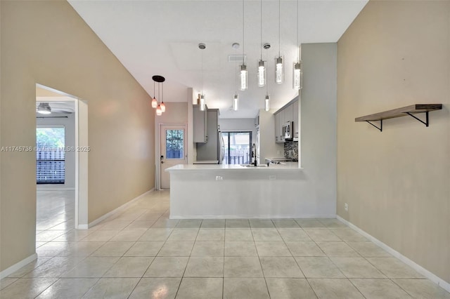 kitchen with light tile patterned floors, sink, backsplash, kitchen peninsula, and hanging light fixtures