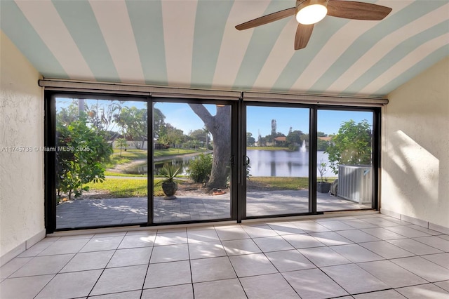 entryway with a water view, light tile patterned flooring, and lofted ceiling