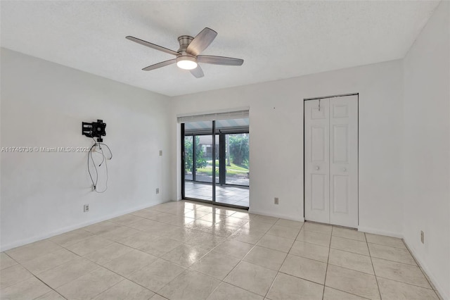 tiled spare room with a textured ceiling and ceiling fan