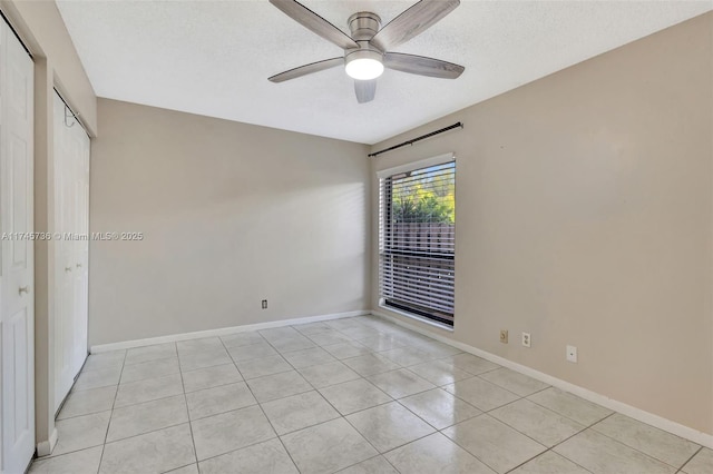 spare room featuring ceiling fan, light tile patterned floors, and a textured ceiling