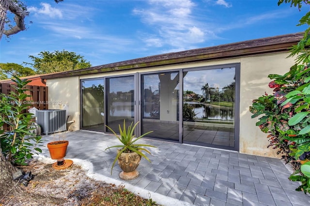 back of house featuring a patio area, a water view, and central AC