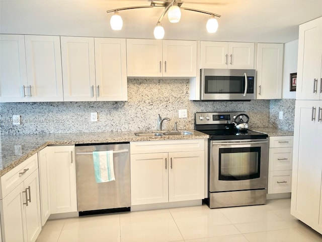 kitchen featuring white cabinets, appliances with stainless steel finishes, sink, and light stone countertops