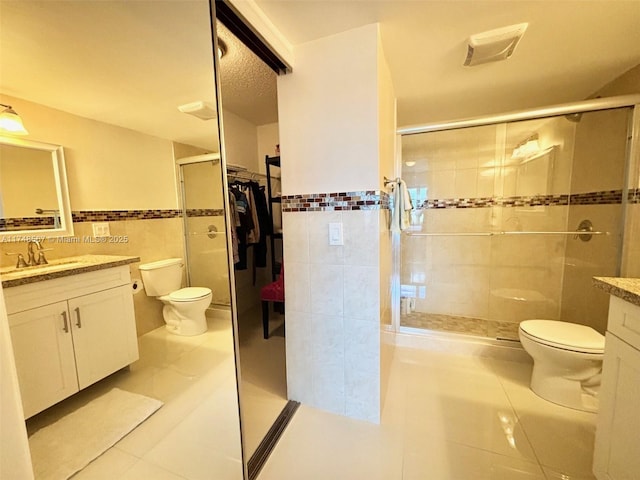 bathroom with toilet, tile walls, tile patterned flooring, and vanity