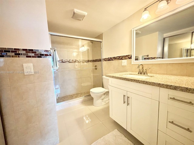 bathroom with an enclosed shower, tile patterned floors, toilet, tile walls, and vanity