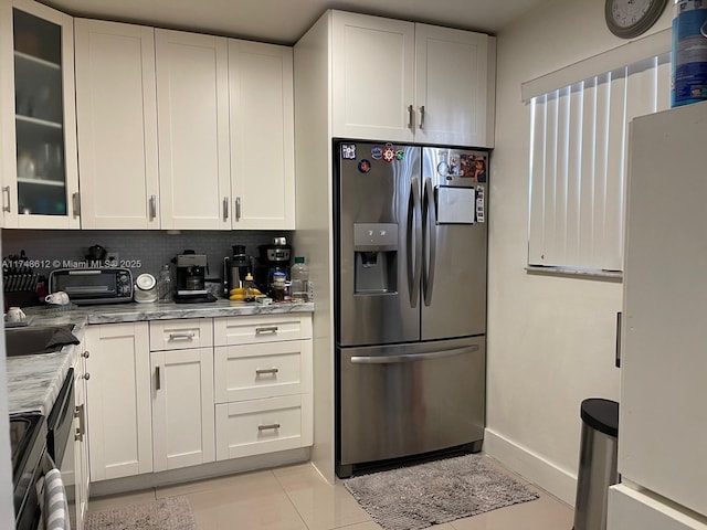 kitchen featuring white cabinetry, white fridge, stainless steel fridge, and light stone counters