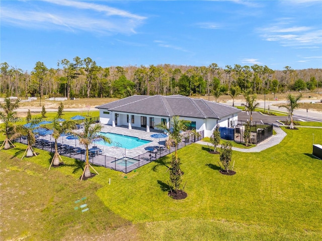 community pool featuring a patio, a lawn, a view of trees, and fence