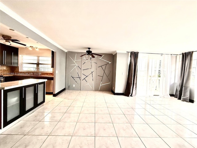 interior space with ornamental molding, ceiling fan, baseboards, and light tile patterned floors