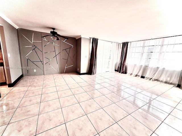 empty room with ornamental molding, ceiling fan, and light tile patterned floors