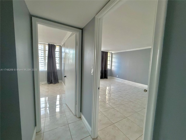 hall featuring baseboards, a wealth of natural light, and light tile patterned flooring