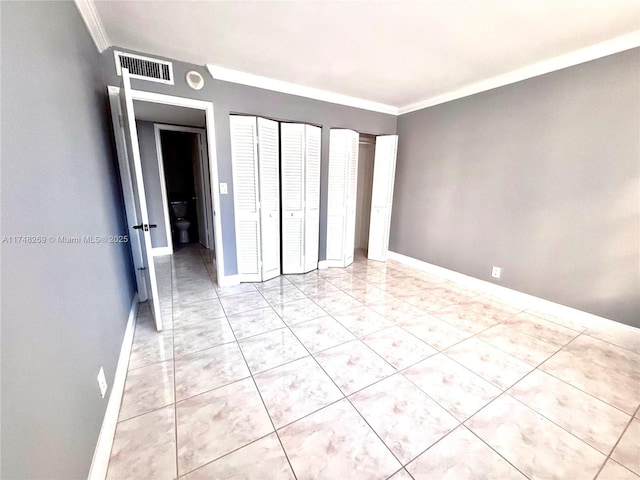 unfurnished bedroom featuring baseboards, visible vents, multiple closets, and ornamental molding