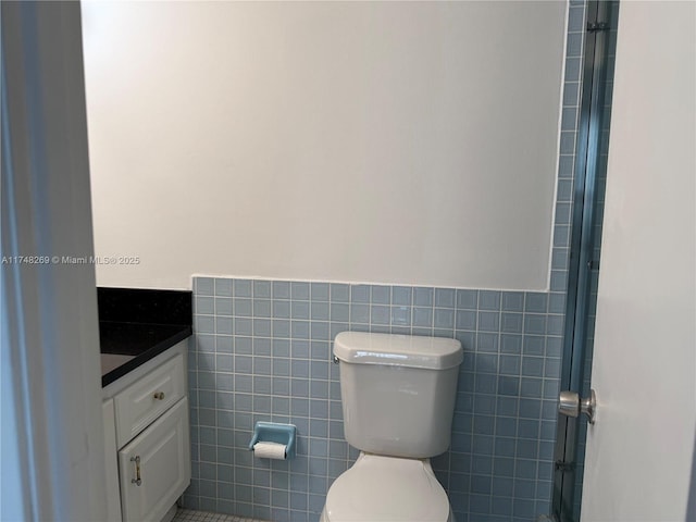 bathroom featuring tile walls, vanity, and toilet