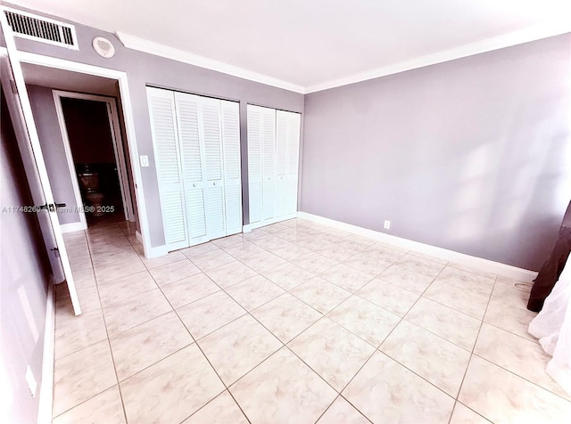 unfurnished bedroom with ornamental molding, two closets, visible vents, and baseboards