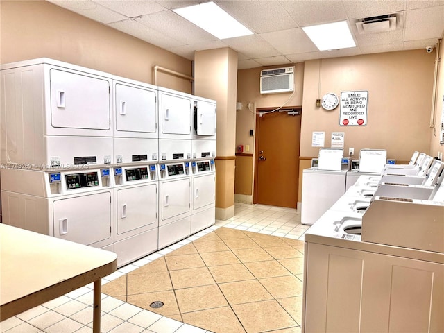 shared laundry area featuring light tile patterned floors, stacked washer / dryer, visible vents, an AC wall unit, and washing machine and clothes dryer
