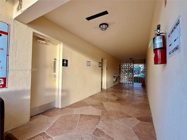 hall with a textured wall and stone tile floors