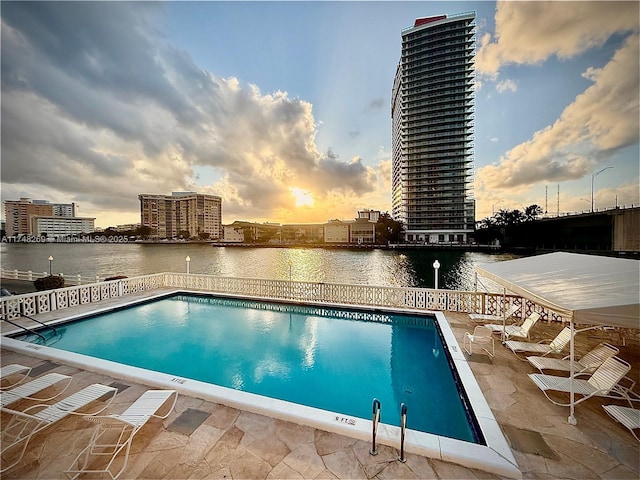pool featuring a water view, a patio area, and a view of city