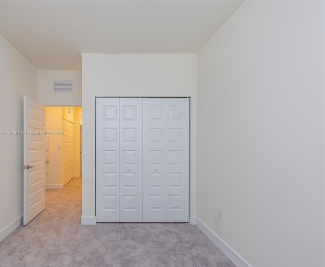 unfurnished bedroom featuring a closet and light colored carpet