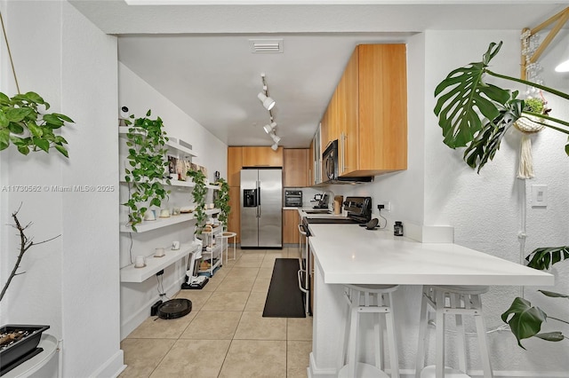 kitchen featuring sink, track lighting, stainless steel appliances, and light tile patterned floors