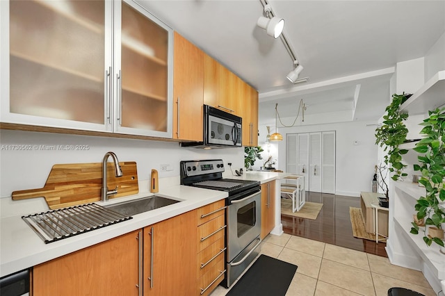 kitchen with track lighting, stainless steel appliances, pendant lighting, light tile patterned floors, and sink