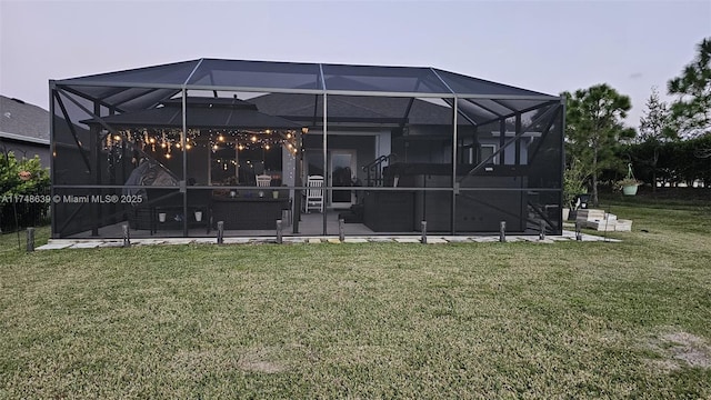 rear view of house with a lanai, a patio area, and a lawn