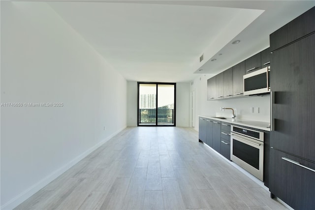 kitchen with white microwave, stainless steel oven, light countertops, expansive windows, and modern cabinets