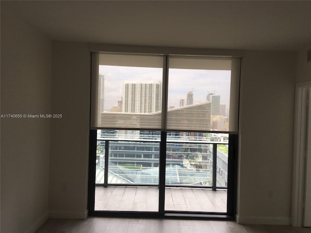 empty room featuring visible vents, a view of city, baseboards, and a wealth of natural light