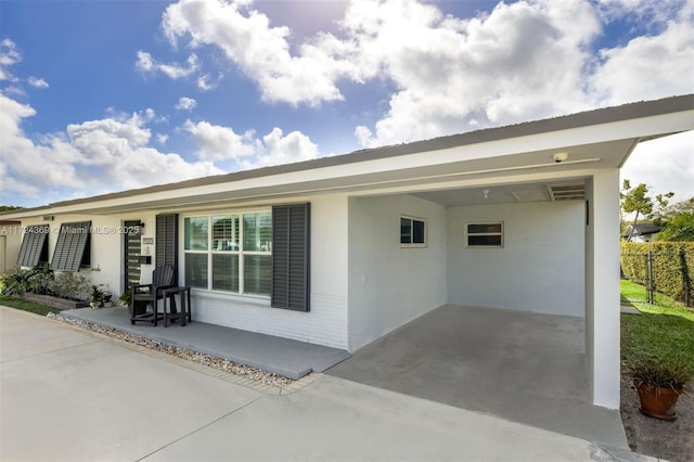 ranch-style home featuring an attached carport, brick siding, fence, and concrete driveway