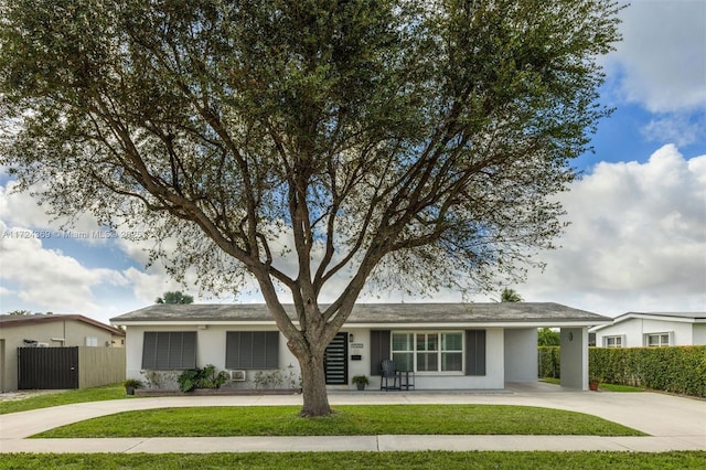 ranch-style home featuring fence, curved driveway, a front yard, and a carport