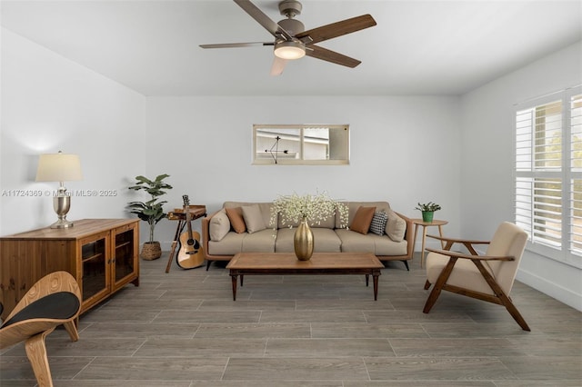 living area featuring a ceiling fan, wood finish floors, baseboards, and a wealth of natural light