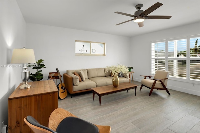 living area with baseboards, light wood finished floors, and ceiling fan