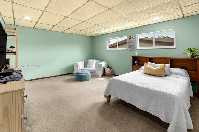 carpeted bedroom featuring baseboards and a drop ceiling