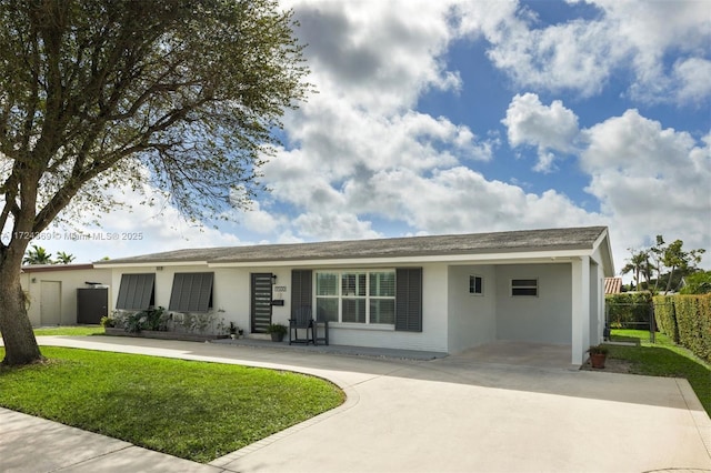 ranch-style home with fence, concrete driveway, an attached carport, a front lawn, and stucco siding