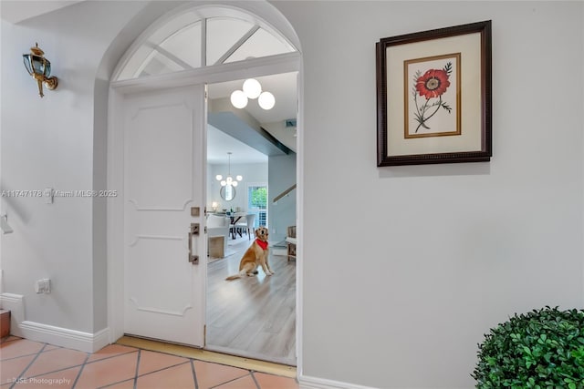 foyer entrance with baseboards, a notable chandelier, and light tile patterned flooring