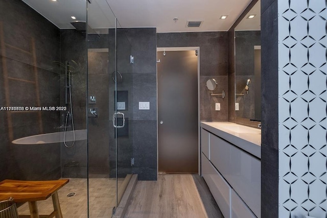 bathroom featuring tile walls, visible vents, a shower stall, vanity, and wood finished floors