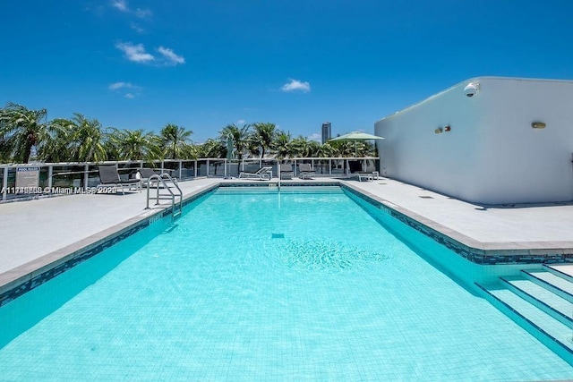 community pool with a patio area and fence