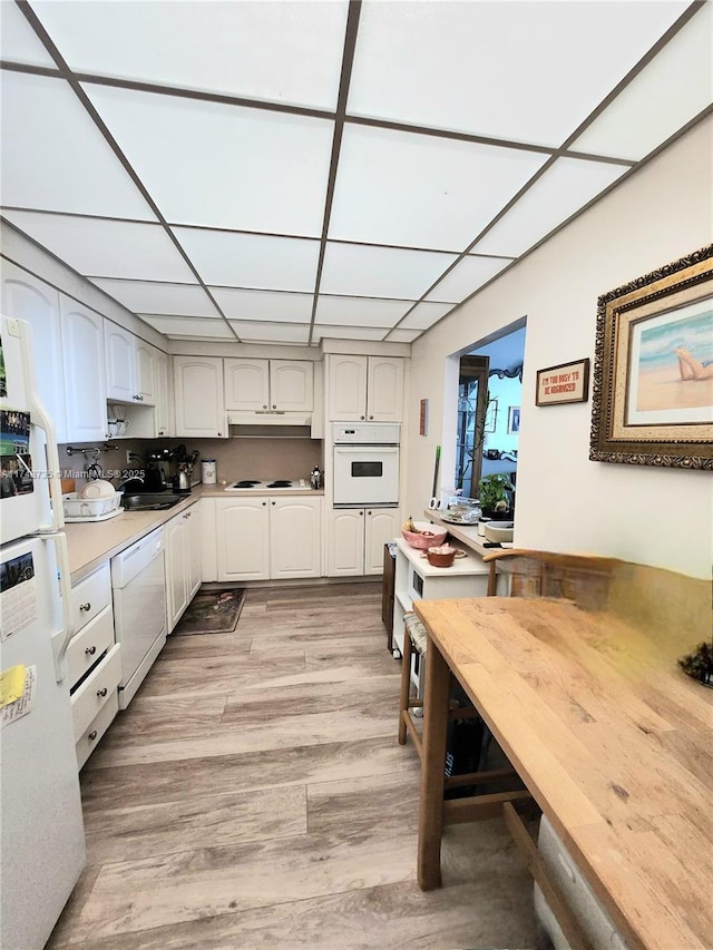 kitchen with light countertops, white appliances, white cabinetry, and light wood-style floors