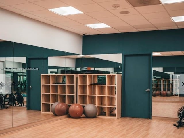 workout area with a drop ceiling and wood finished floors