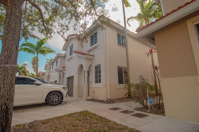 view of home's exterior with a tiled roof, concrete driveway, and stucco siding